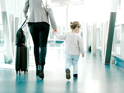 Mother holder her daughter's hand walking through the airport terminal