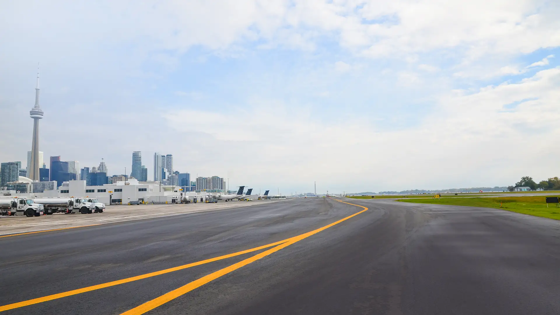 Photo centered on the Corbit Barot Airpot runway with planes and the Toronto skyline in the background