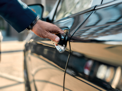 Male hand opening the door of a black car while standing outdoors