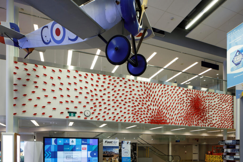 red art installation at airport near a plane replica